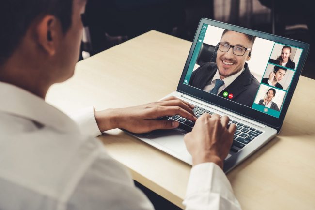 Photo of man in front of laptop illustrates blog "How to Prepare for a Virtual Job Interview"
