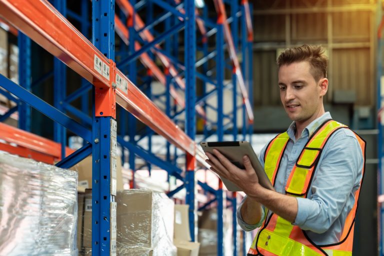 Photo of man with safety vest and tablet in warehouse illustrates blog: " Warehouse Jobs vs Retail: Which Is the Best Fit for You?"