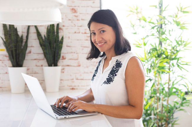 AdministrativeAssistant2 Photo of smiling woman typing on laptop illustrates blog: "Administrative Assistant Job Duties"