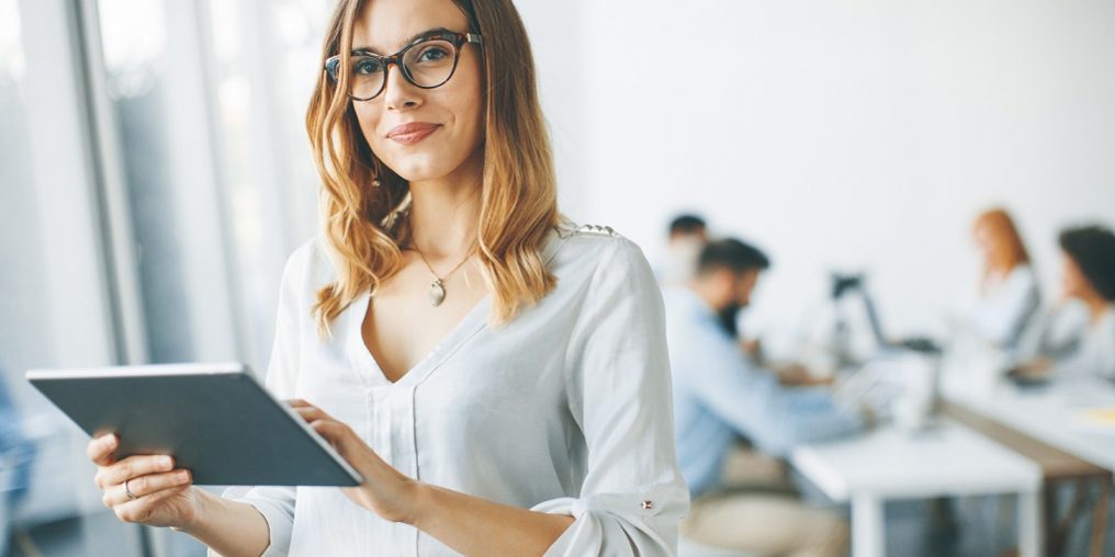 Photo of woman holding tablet illustrates blog: "The Most Important Clerical Skills To Add to Your Resume"