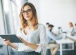 Photo of woman holding tablet illustrates blog: "The Most Important Clerical Skills To Add to Your Resume"