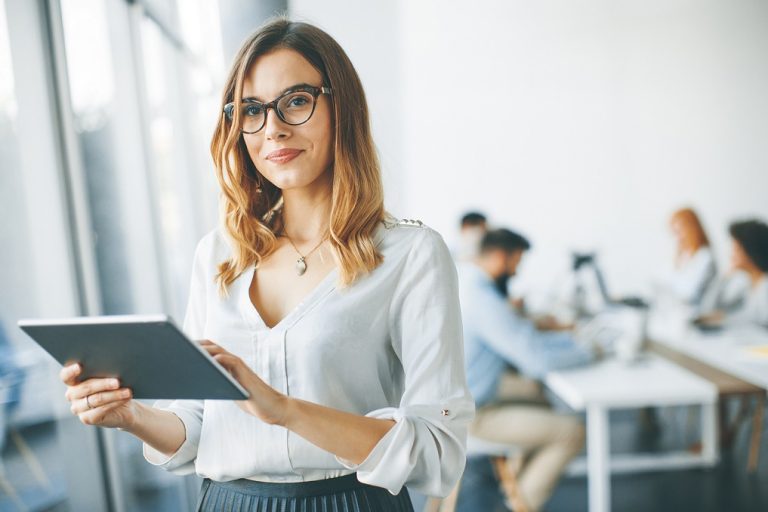 Photo of woman holding tablet illustrates blog: "The Most Important Clerical Skills To Add to Your Resume"
